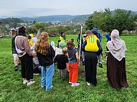 Gruppe von Kindern und Betreuern auf einem Feld, mit dem Rücken zum Betrachter stehend