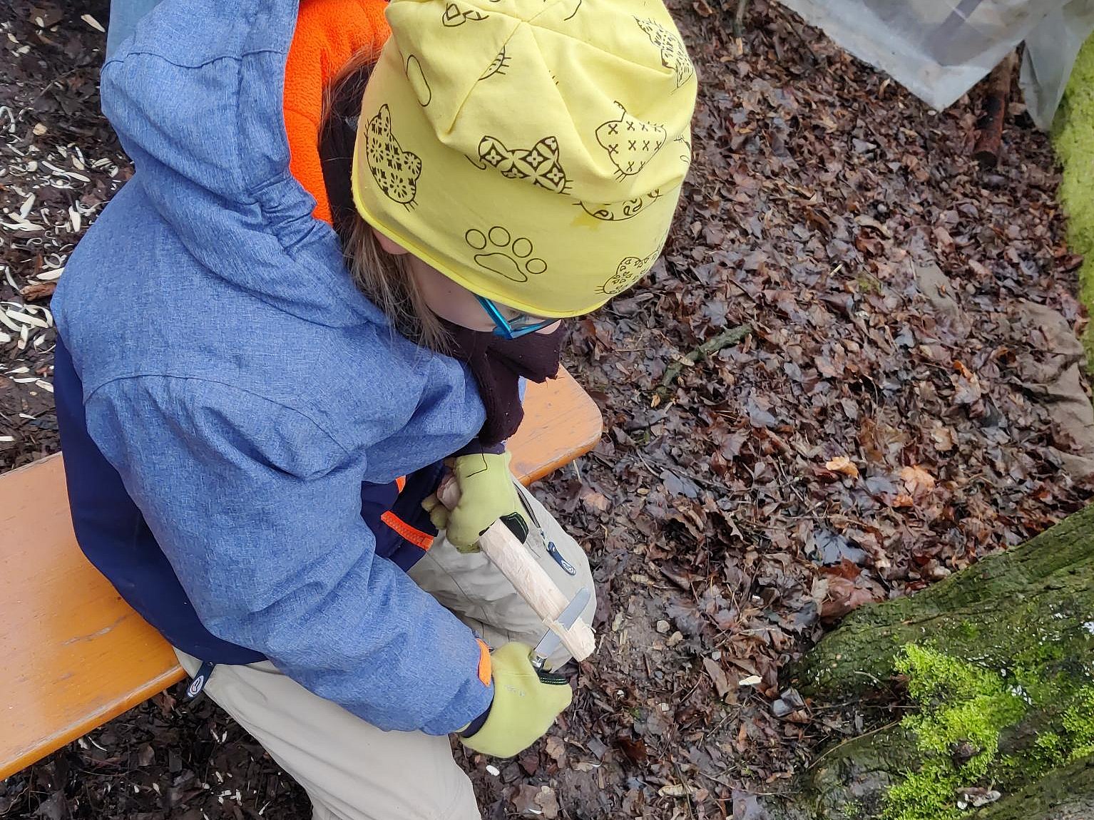 Kind im Freien sitzend, schnitzt einen Stock