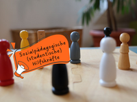 Spielfiguren auf einem Holzbrett - Text in Sprechblase: Sozialpädagogische studentische Hilfskräfte