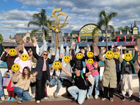 Gruppe von Kindern mit Betreuer:innen vor einem Brunnen im Europark, alle strecken die Hände in die Luft, die Gesichter der Kinder sind mit "Smileys" unkenntlich gemacht