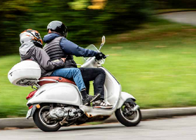 Titelbild der Broschüre, Erwachsener und Kind auf einem Motorroller fahrend, seitlich fotografiert