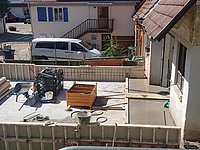 Blick von oben auf Baustelle, Bodenplatte und rundum ca. 1 m hohe Schalungswände sind zu sehen