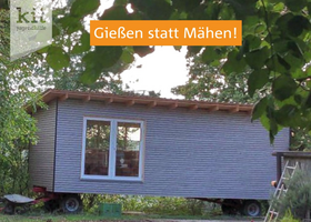 Hellblauer Bauwagen in grüner, bewachsener Umgebung