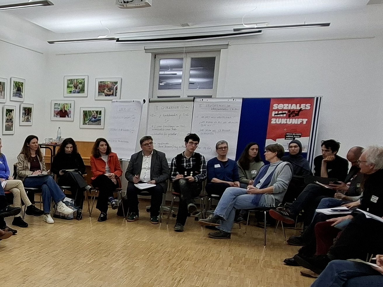 Blick in einen Veranstaltungssaal, viele Menschen sitzen im Kreis, unter ihnen sitzen Kandidierende zur Landtagswahl