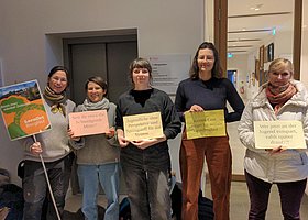 fünf Mitarbeiterinnen der kit jugendhilfe mit Protestschildern stehen in einer Reihe und blicken in die Kamera